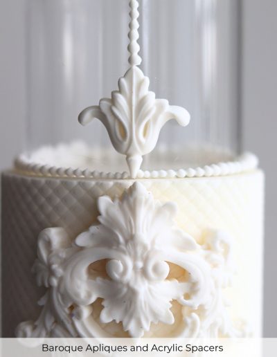 Close-up of a luxury wedding cake with baroque appliques and a clear acrylic spacer tier