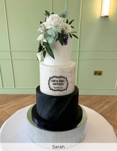 Black and white three tier wedding cake with textured tier and sugar floral topper