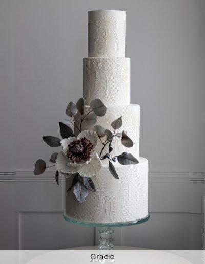 Tall embroidered ivory wedding cake with dark floral sugar details