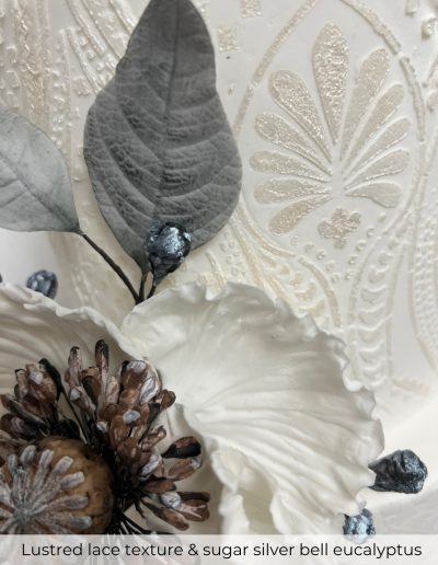 Close-up of sugar silver bell eucalyptus and lace-textured wedding cake