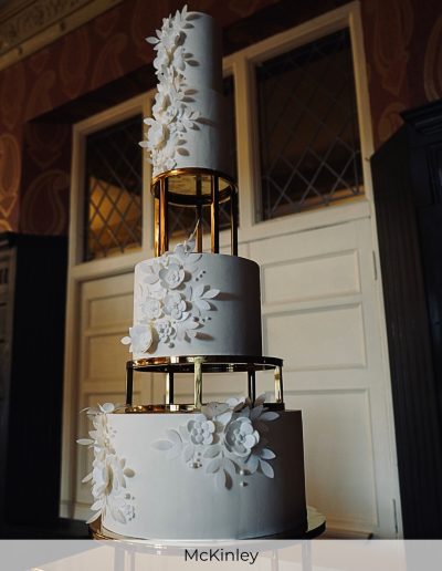 Tall white wedding cake with gold spacers and cascading sugar flowers