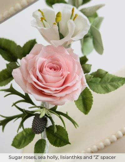 Pink sugar rose with sea holly and lisianthus on wedding cake