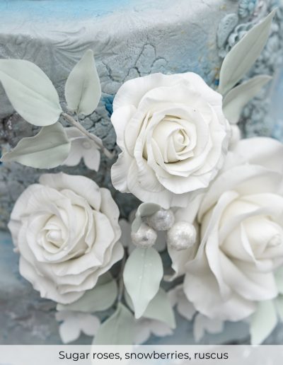 White sugar roses paired with frosty snowberries and ruscus leaves