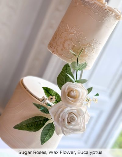 Sugar roses, wax flower and eucalyptus on suspended wedding cake tier