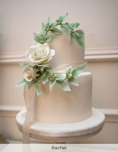Elegant white wedding cake with ivory sugar roses and trailing leafy wreath