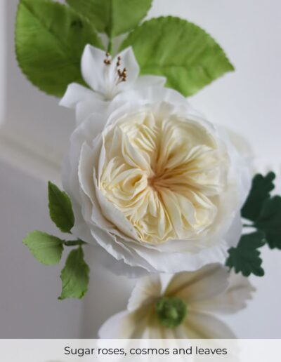 Handcrafted sugar roses and cosmos with fresh green foliage on a bespoke luxury multicultural wedding cake at Bosworth Hall Warwickshire