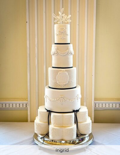 Luxury bespoke white wedding cake with handcrafted sugar lace and monogram detailing, designed for a wedding at Buxton Crescent Hotel