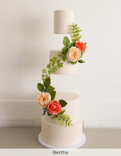 Tall floating ivory wedding cake with separated tiers, peach sugar roses, coral flowers, fern and cascading ivy.