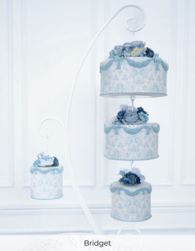 Four powder blue wedding cakes displayed on chandelier white stands with damask patterns, swags and flowers.