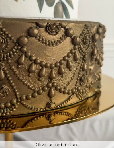 Olive-gold wedding cake tier decorated with raised beads, roses, chains and teardrop jewellery details.