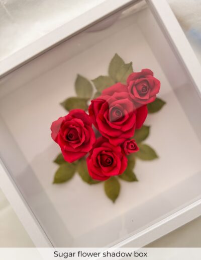 Handcrafted red sugar roses and green leaves preserved inside a white wedding flower shadow box.