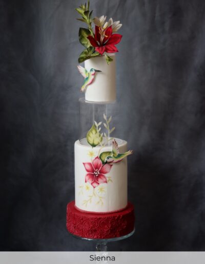 Tall ivory and red wedding cake with tropical sugar lilies, hand-painted flowers, hummingbirds and a clear acrylic spacer.